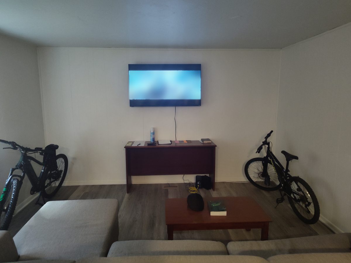 Shared living room with a wall-mounted TV and sectional sofa in a Tina Marie's men's sober living home in Ohio